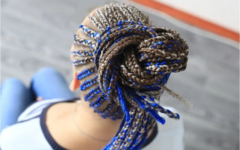 Woman is about to get scalp sores from tight braids tied with blue ribbon and yarn in her hair