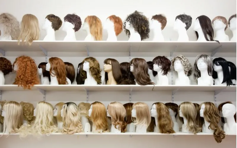 Row of mannequins with various types of wigs for black women sitting on shelves