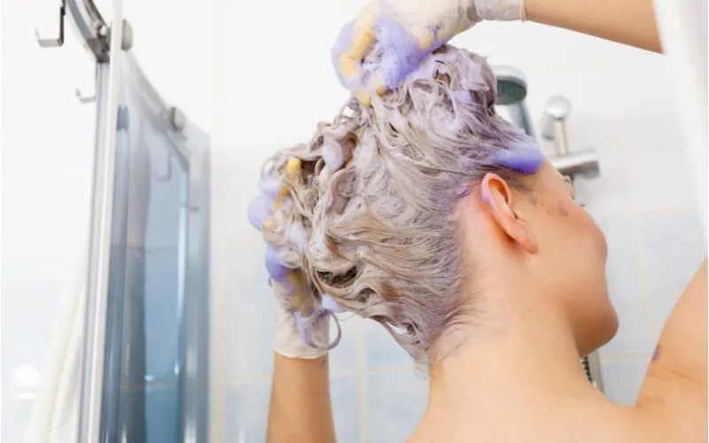 Woman using the best blue toner for orange hair in the shower