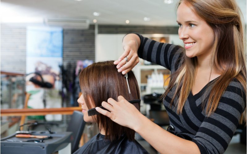 Woman getting a haircut in a salon for a piece on what is a trim haircut