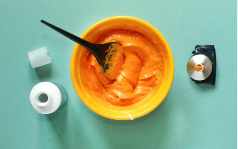 Aerial view of someone mixing hair dye with conditioner in an orange bowl