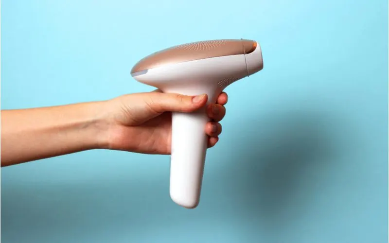 The best at-home laser hair remover held by a woman in a blue room