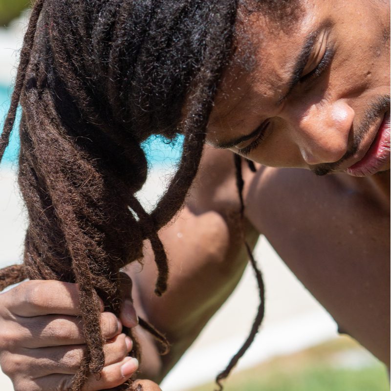 Guy bending over twisting his locs to fix the dreadlocks thinning at root