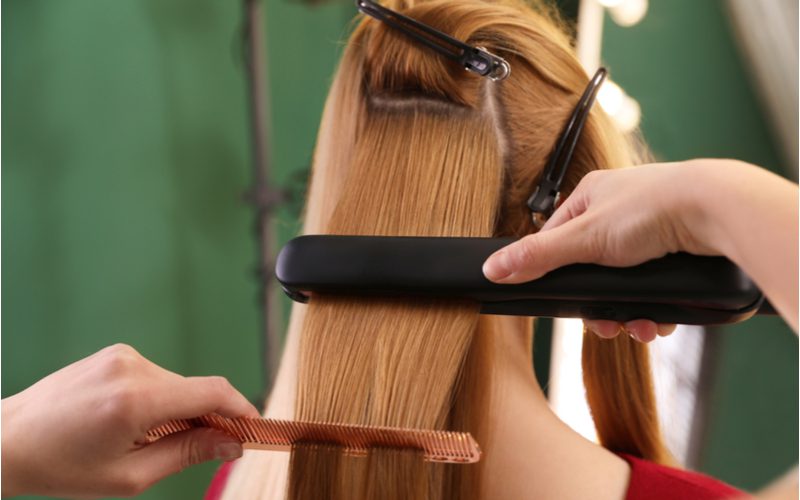 Woman using the best flat iron for beach waves on her hair