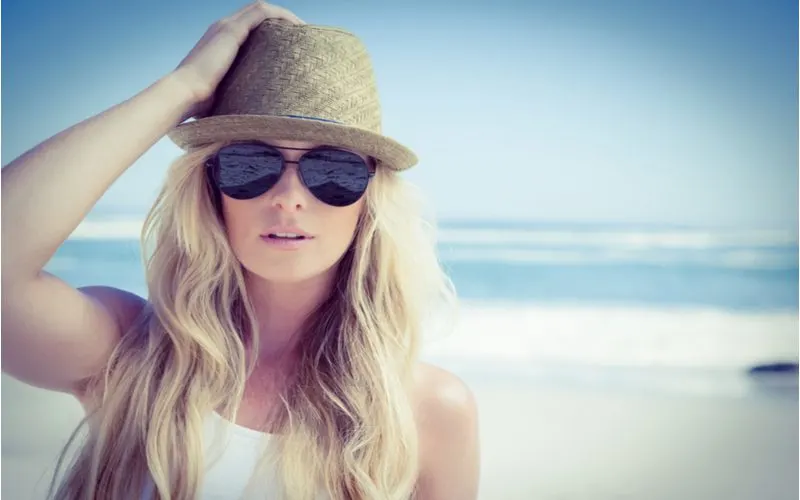 Woman who just used the best flat iron for beach waves wears a hat