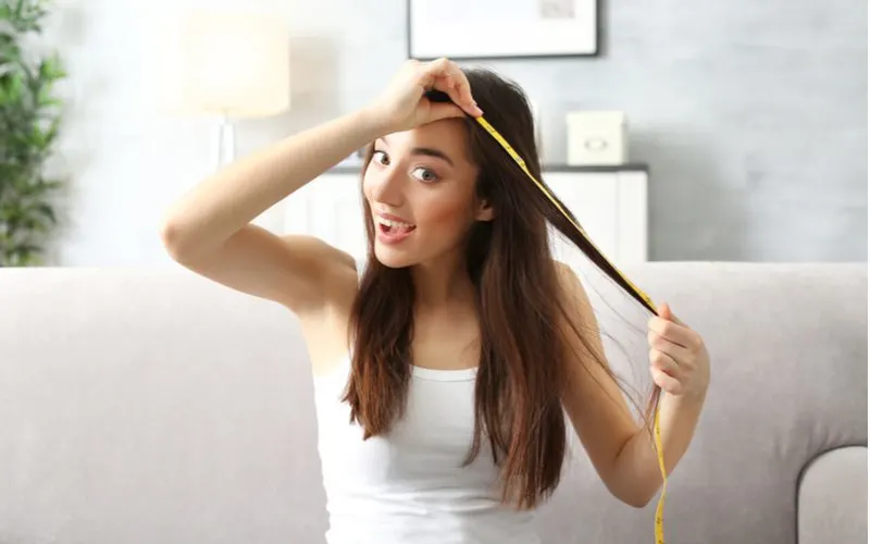 Woman measuring her hair after using collagen for hair growth