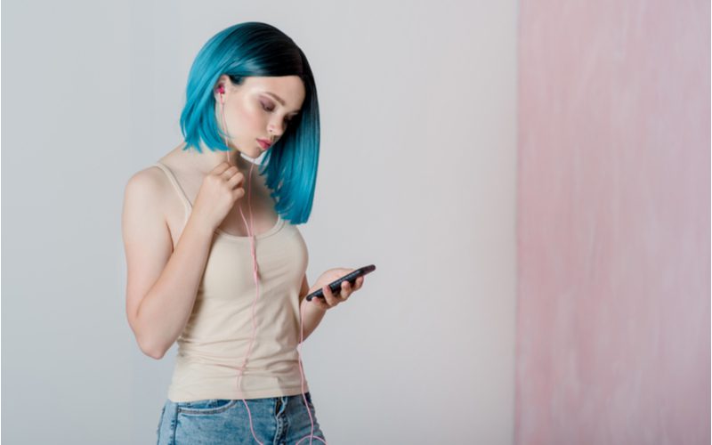 Gorgeous thin woman with a blue hair looks at an iphone for a piece on the best shampoo for blue hair