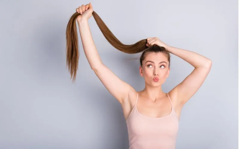 Piece on how to do an extended ponytail with a woman holding her hair