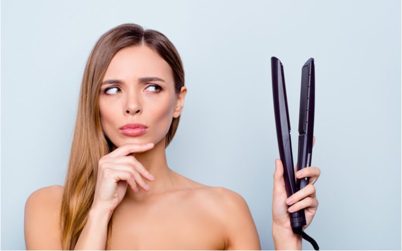 Image showing how to style curtain bangs with flat iron featuring a woman holding a hot iron