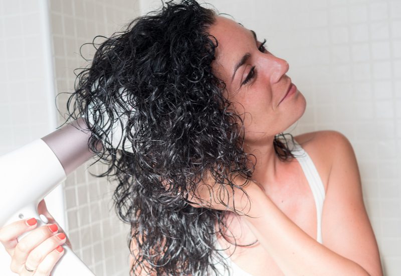 Smiling woman activating her curls with a diffuser