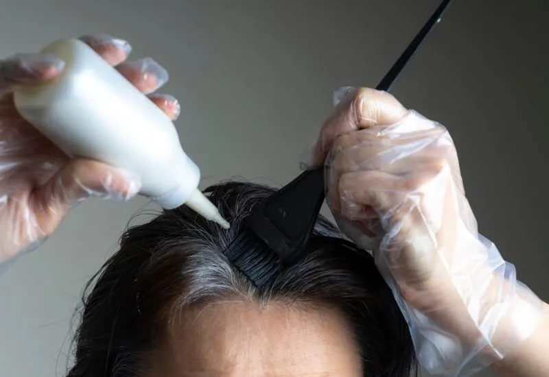 Woman using demi-permanent hair color on her roots
