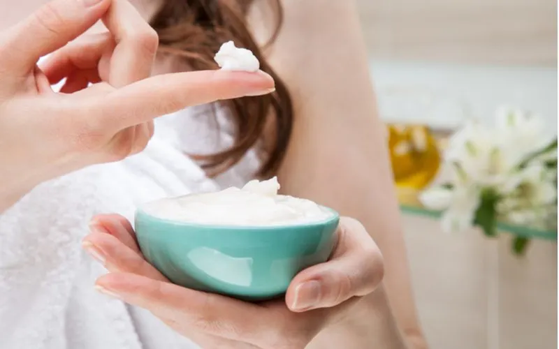 Woman dipping her finger in the best curl cream for wavy hair