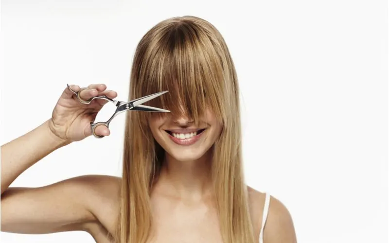 Woman showing us how to cut face-framing layers with her shears or clippers