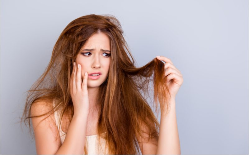 Woman sad because she didn't use the best shampoo for long hair and now her hair is damaged and tangled