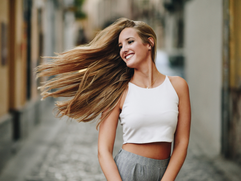 Happy young woman with the 1B hair type in an old town style street