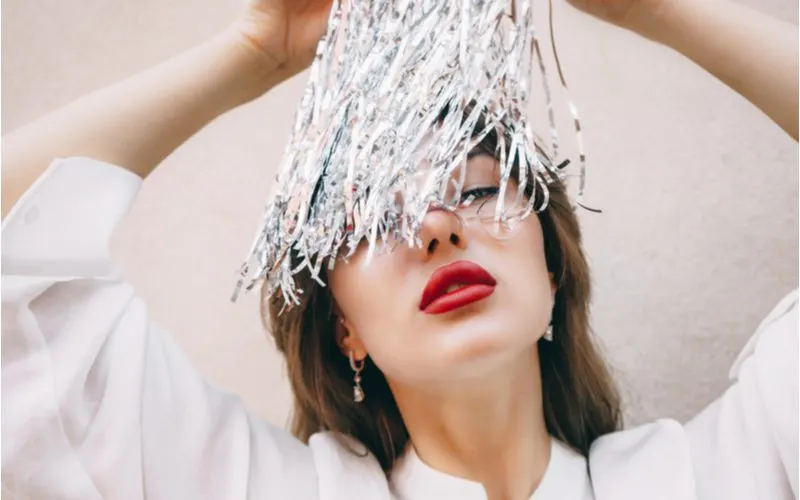 Girl with red lip holding hair tinsel above her eyes
