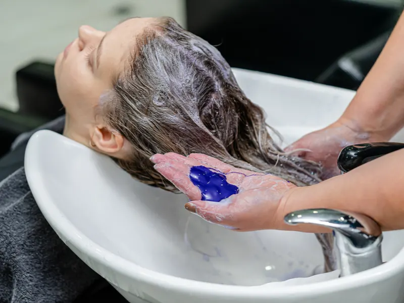 Piece on what is hair stain featuring a woman using purple shampoo