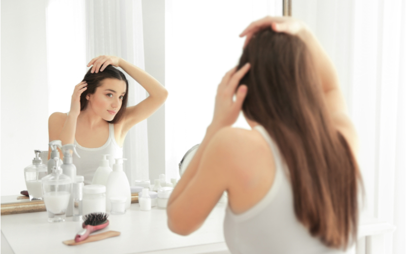 Người phụ nữ đang sử dụng một trong những loại dầu gội có lượng tốt nhất trên tóc của mình cho một loại dầu gội có tiêu đề What Are Volume Shampoos