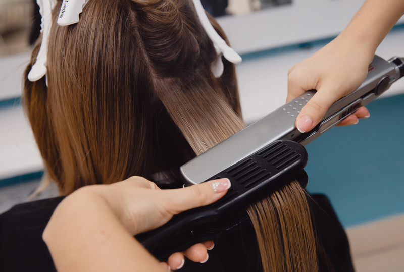 Woman getting a keratin treatment for a piece titled do keratin treatments cause hair loss