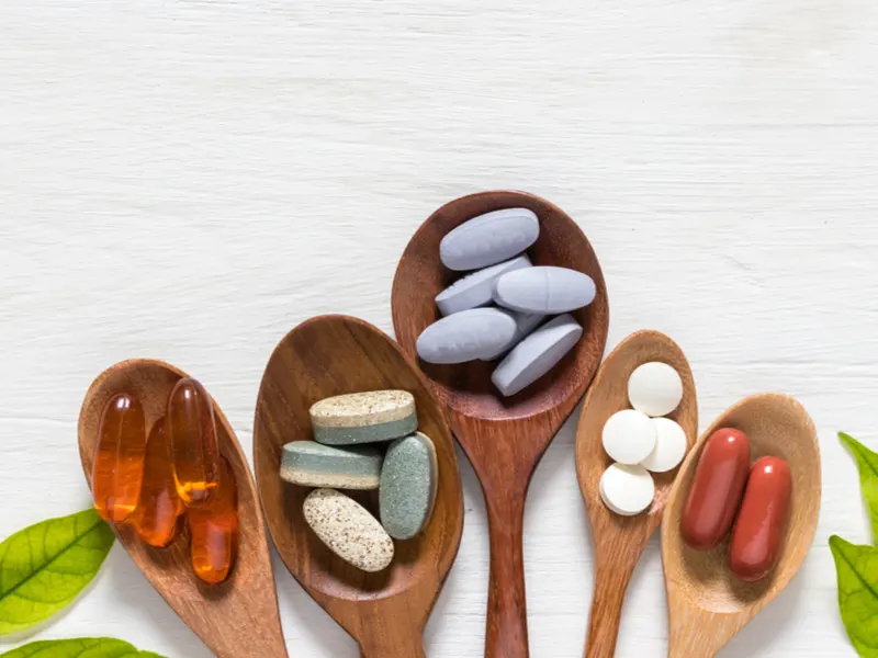 Image of a bunch of vitamins on spoons for a piece on which vitamin deficiency causes hair loss