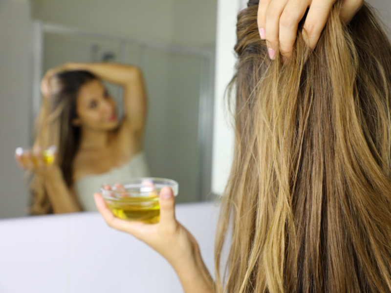 Woman using macadamia nut oil vs argan oil for hair styling