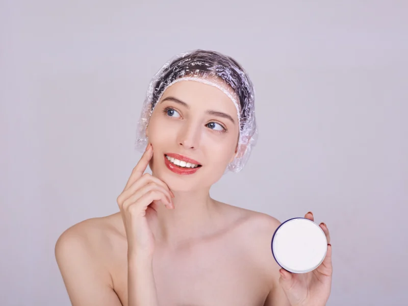 Woman wondering, What Are Shower Caps For while holding hair product