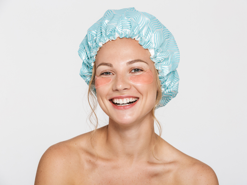 Woman showing us what shower caps are for while wearing one in a studio