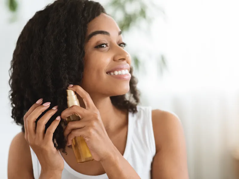 Happy black woman using macadamia oil vs argan oil for hair