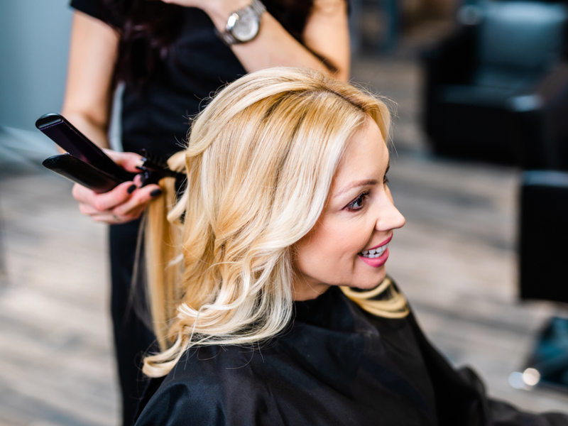 Hair stylist blonding a woman in her salon chair