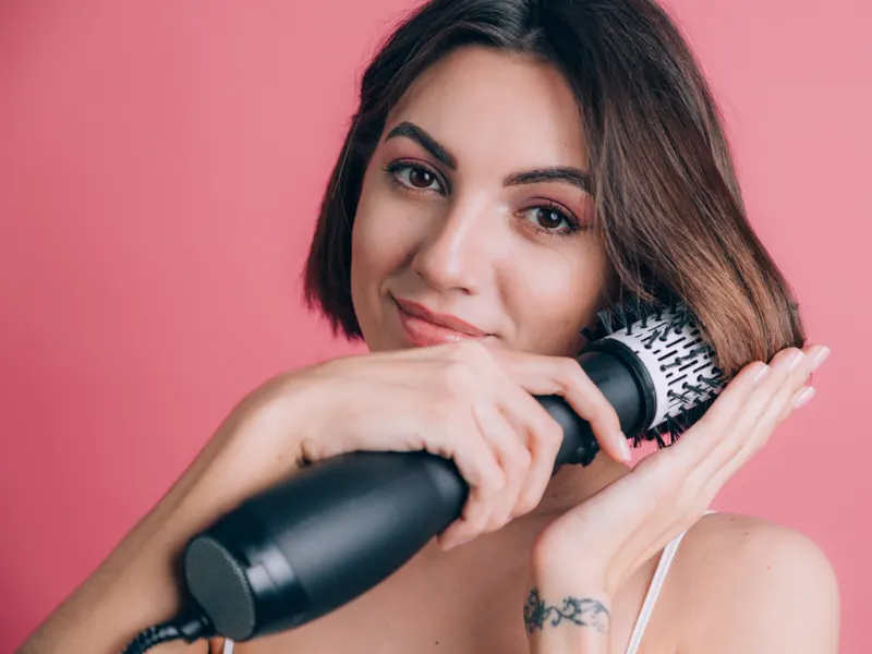 Smiling woman making curls with her round brush