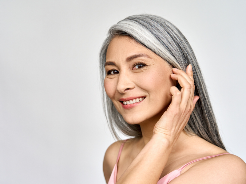 Woman growing out her gray hair that is colored and smiling