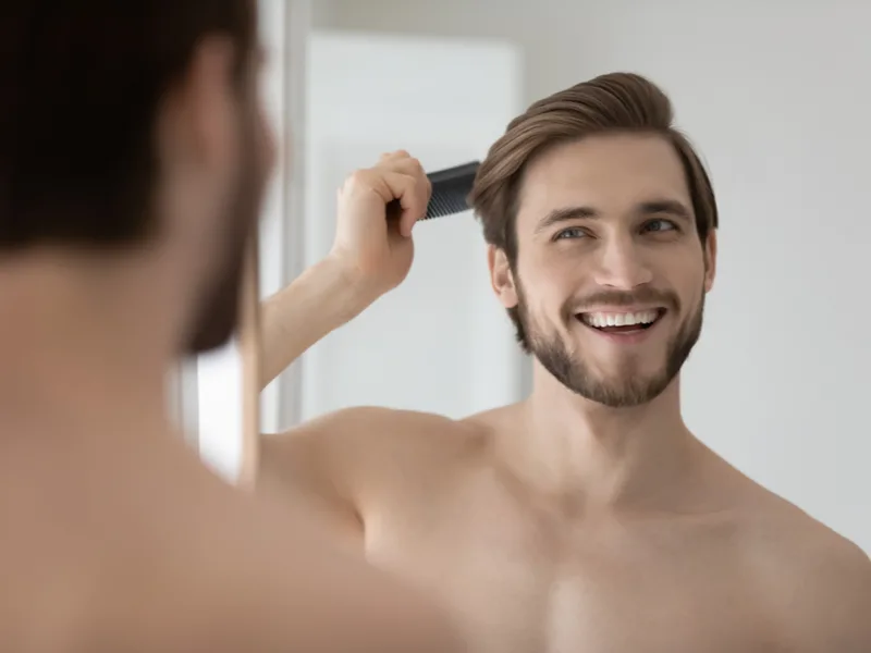 Man who didn't wonder, "should I get a hair transplant" brushing his thick hair back