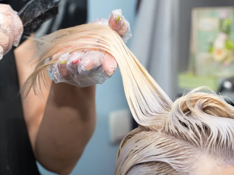 Hairdresser blonding a woman's hair with bleach