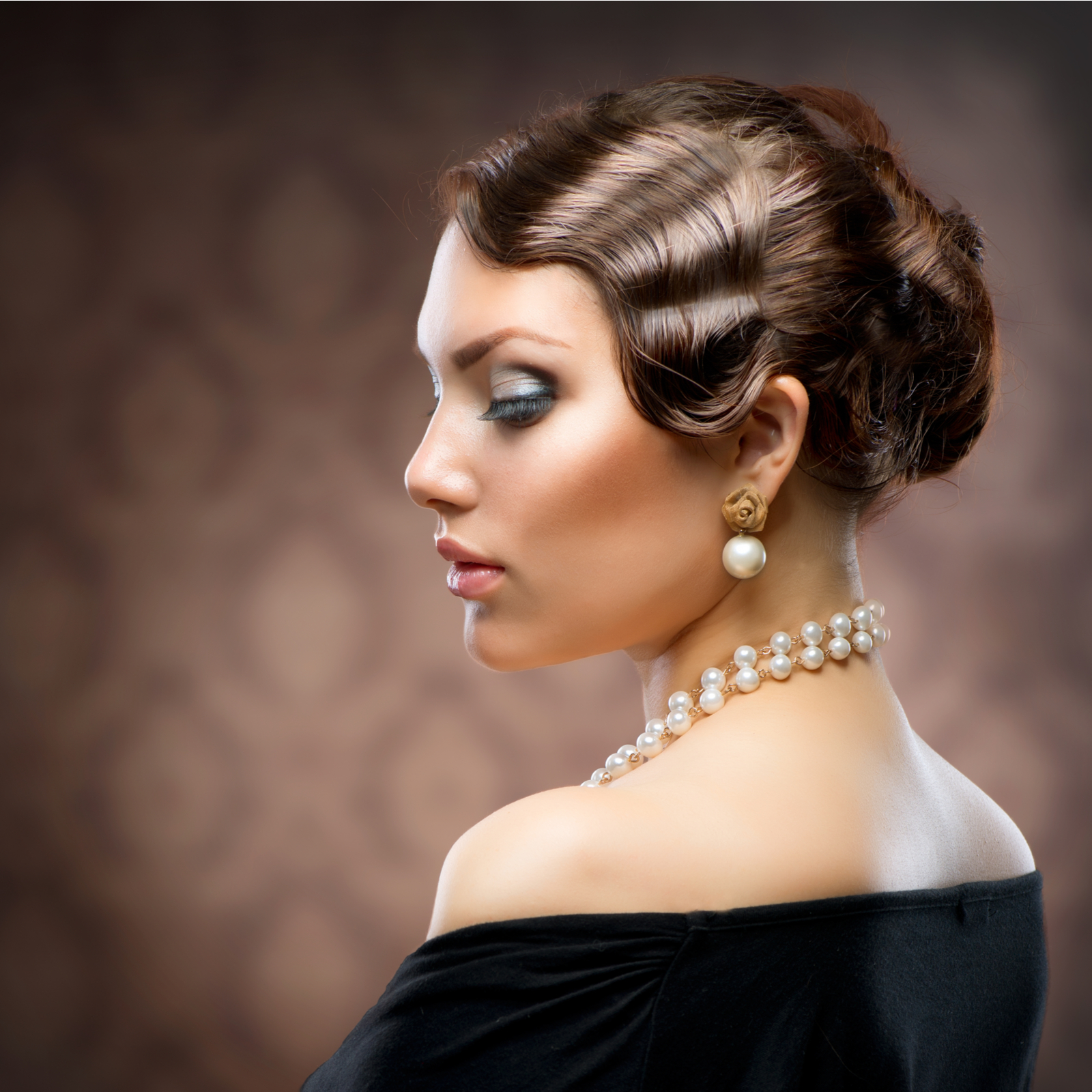 Retro looking woman with finger waves and pearls looks glam in a side profile photo