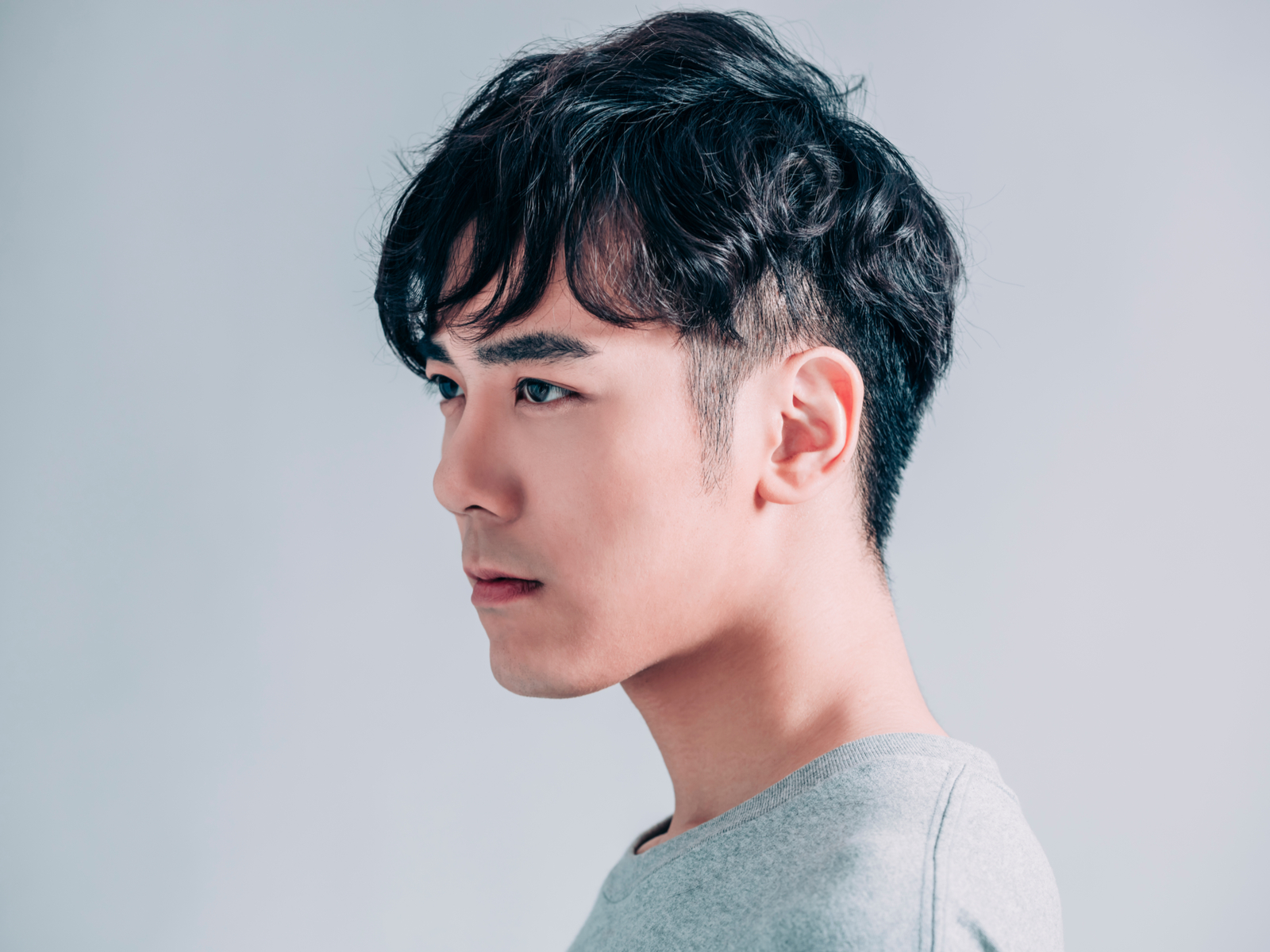 Photo of one of the best kpop hairstyles, the Messy Two Block Cut, pictured on a guy in a grey shirt