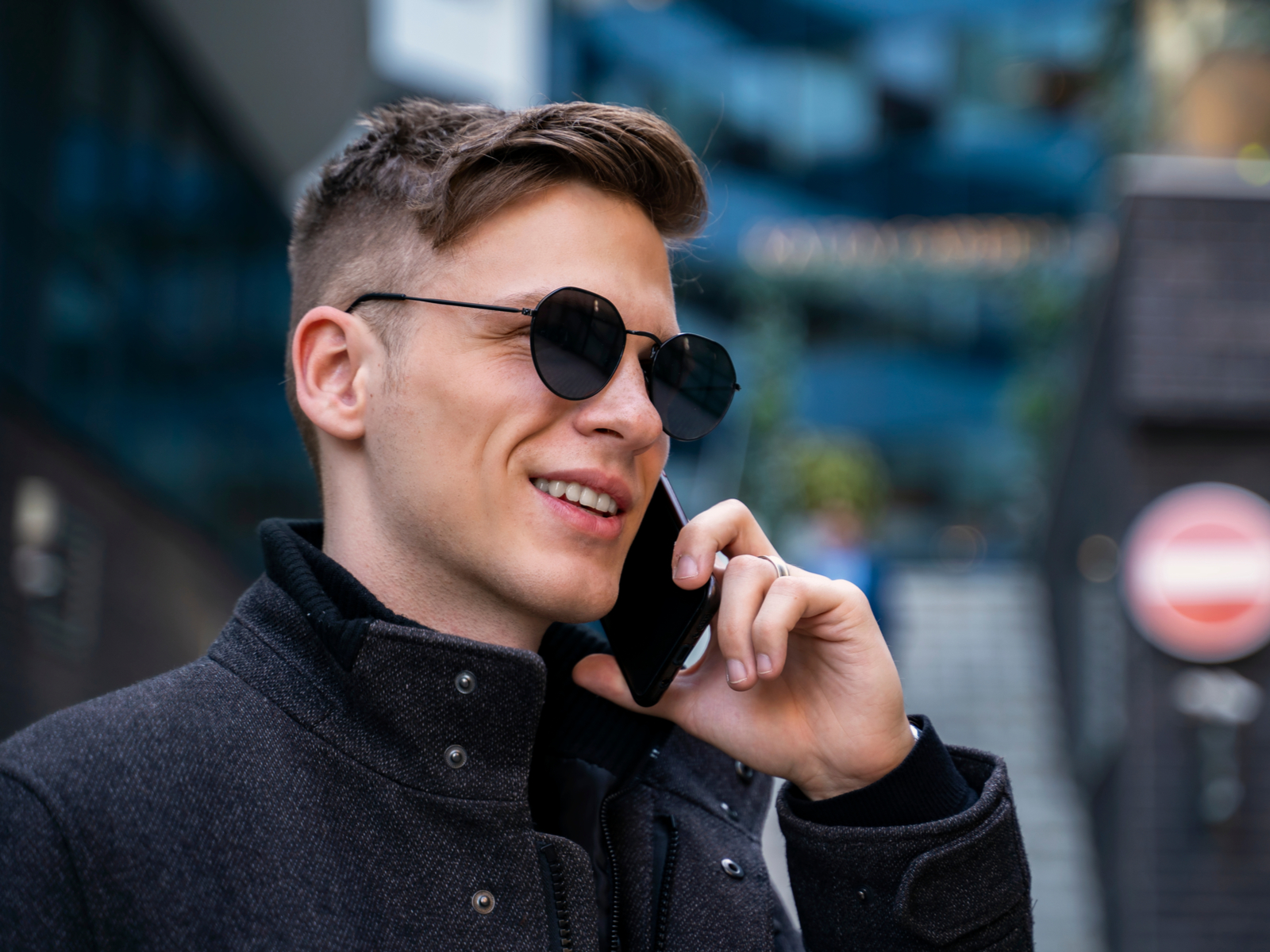As a featured straight hair men's hairstyle, a High Fade With Rolled Quiff is pictured on a guy talking on his phone