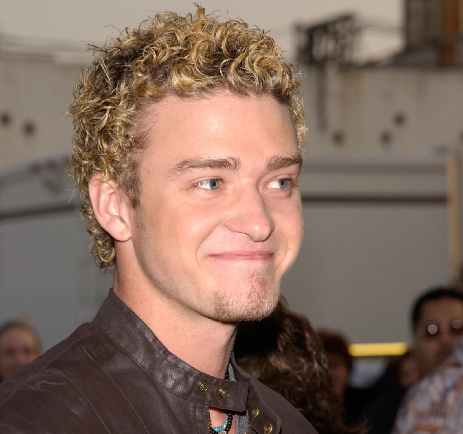 Justin Timberlake (with frosted tips) grinning at a premier event in a leather jacket