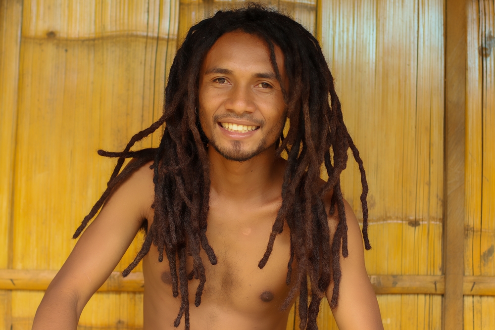 For a piece titled How Long Does It Take to Grow Dreads, a guy with locs smiling without a shirt
