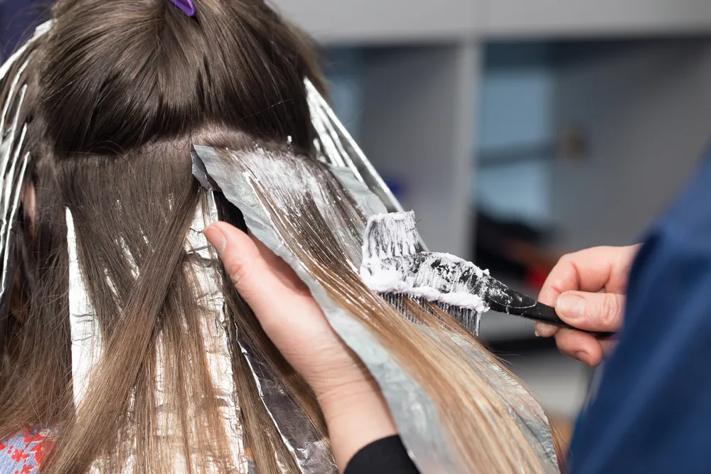 Image depicting a hair stylist showing us how to bleach black hair in an up-close image