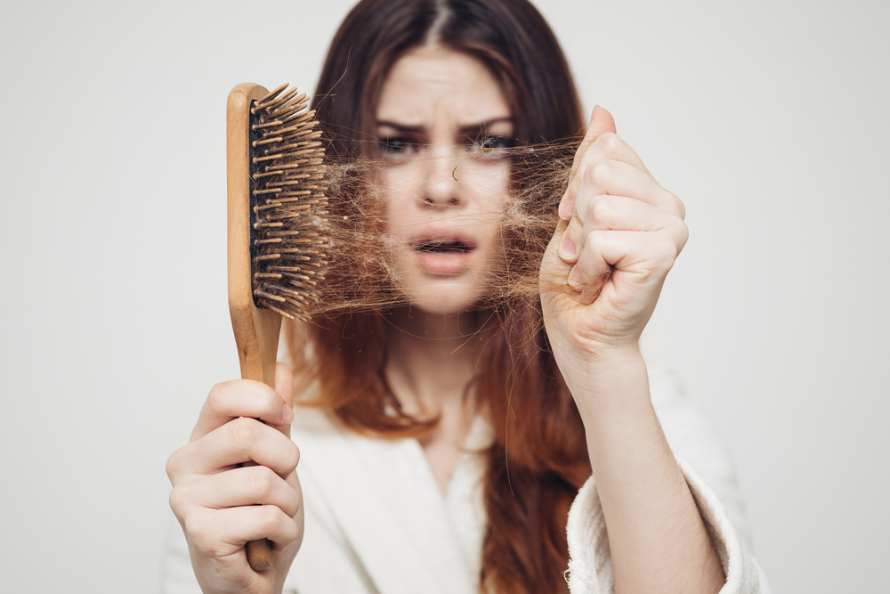 Woman holding a brush up to the camera for a piece titled How Many Hair Strands Are on a Head
