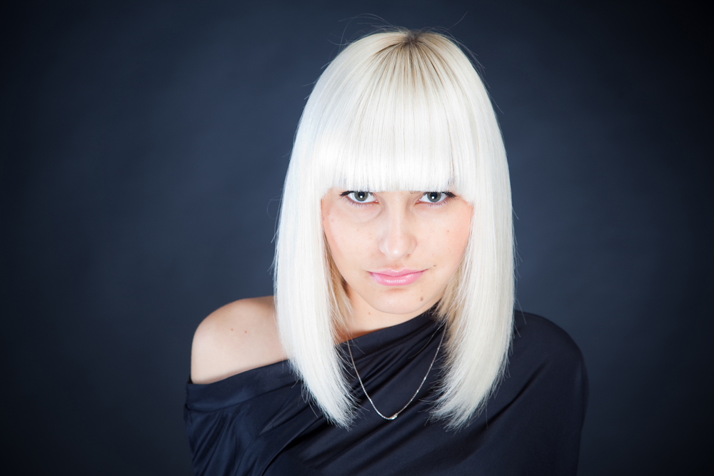 Woman with platinum blonde hair smiles at the camera sensually
