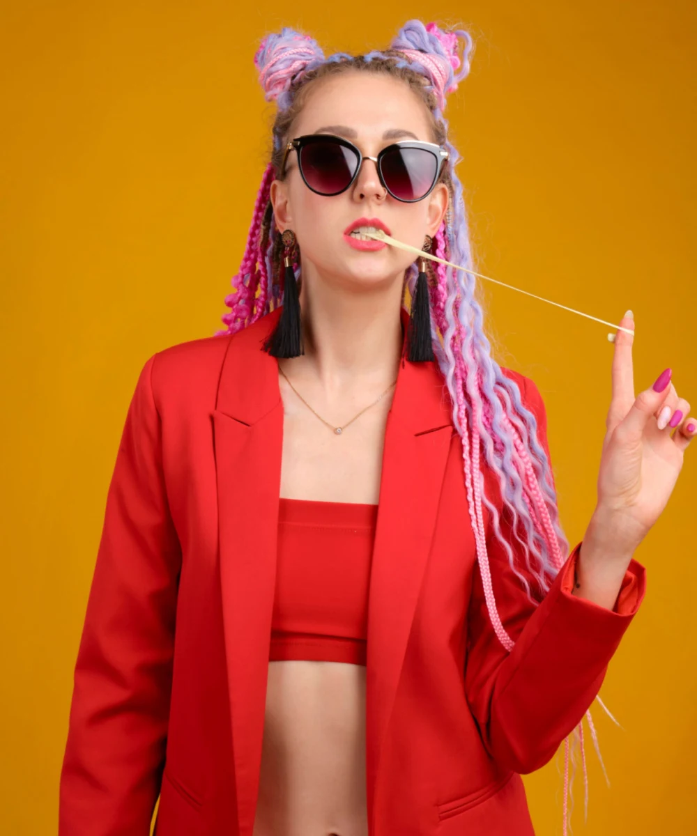 Pussy Cat wick dreads hairstyle on a woman in a red sports bra and overcoat