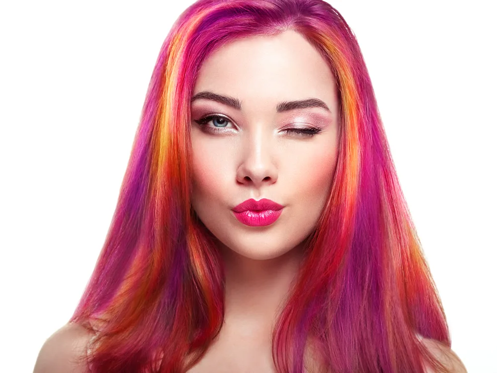 Magenta Sunset, a great unnatural hair color for blue eyes, pictured on a woman in red lip puckering her lips with fair skin