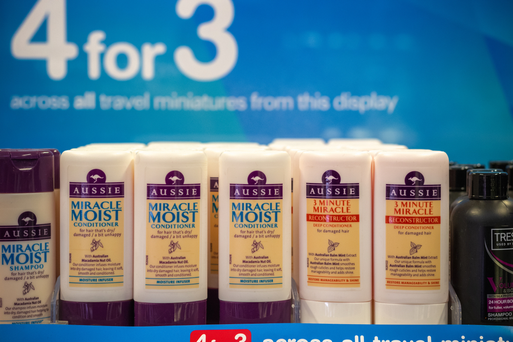 A bunch of Aussie shampoo on a shelf in an airport to help answer if it's good for hair