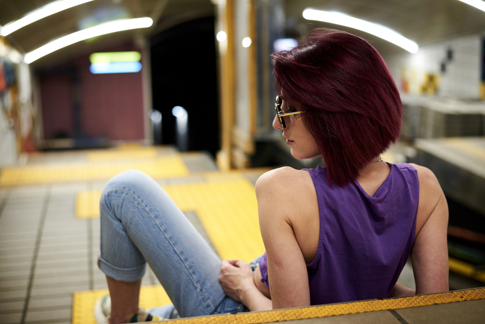 Plum burgundy hair color on a woman lying down in a subway tunnel