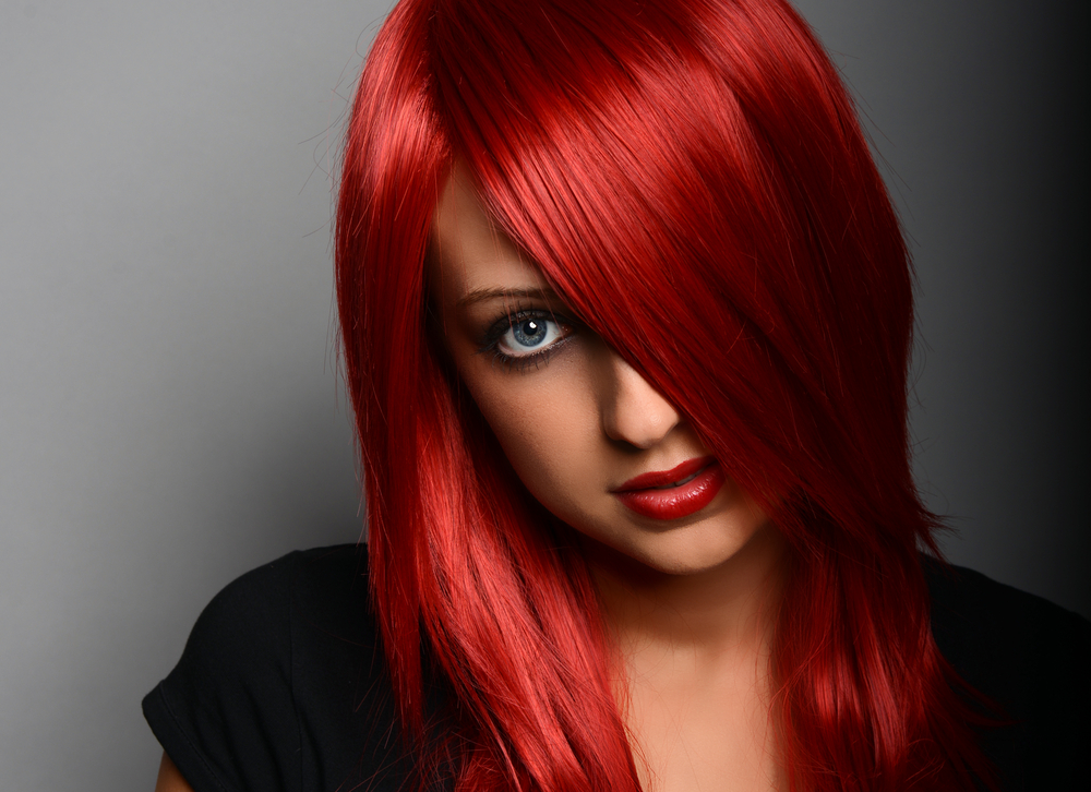 Bright Scarlet unnatural hair color for blue eyes on a woman sensually looking at the camera in red lip