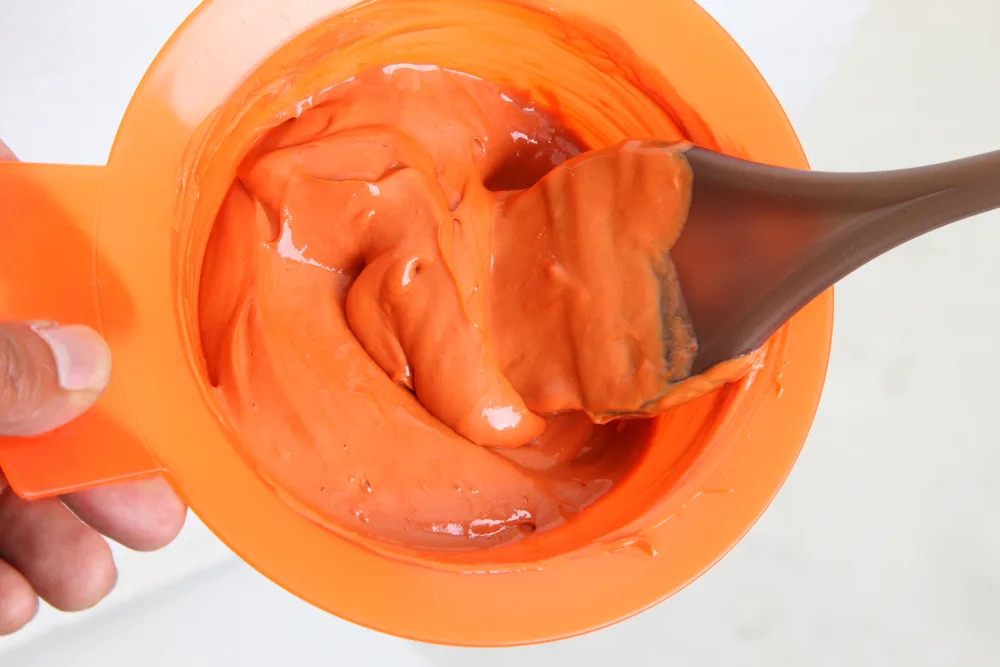 Image of a mixing bowl with orange dye in it for a piece titled orange hair color ideas
