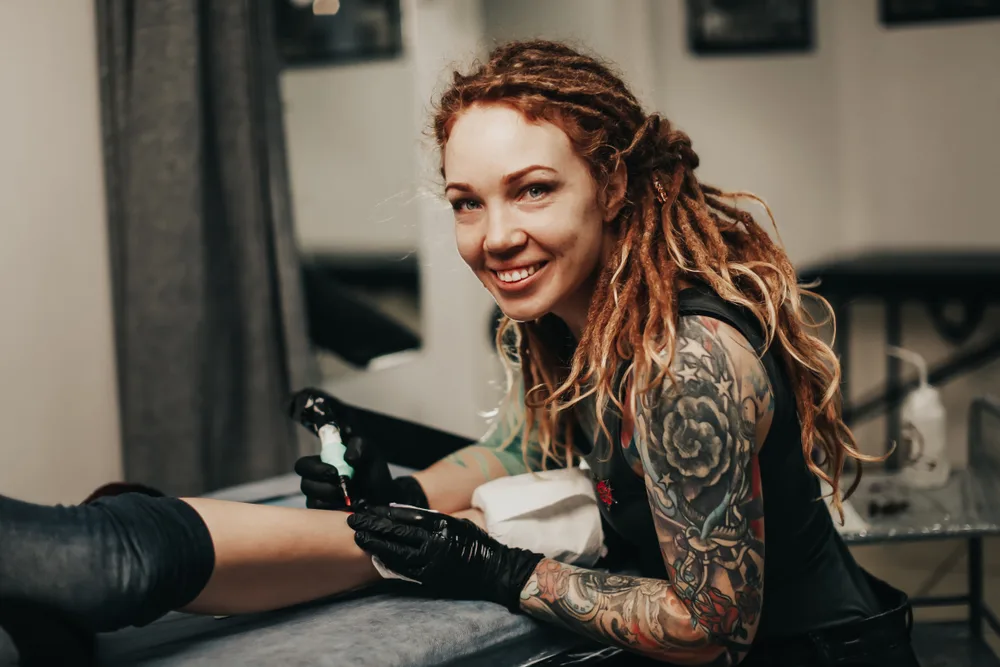 For a piece on how to dread white hair, a tattoo artist smiles at the camera
