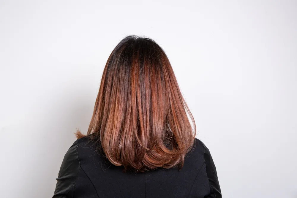 Lustrous Chestnut Balayage Red Brown Hair Color on a woman looking away from the camera