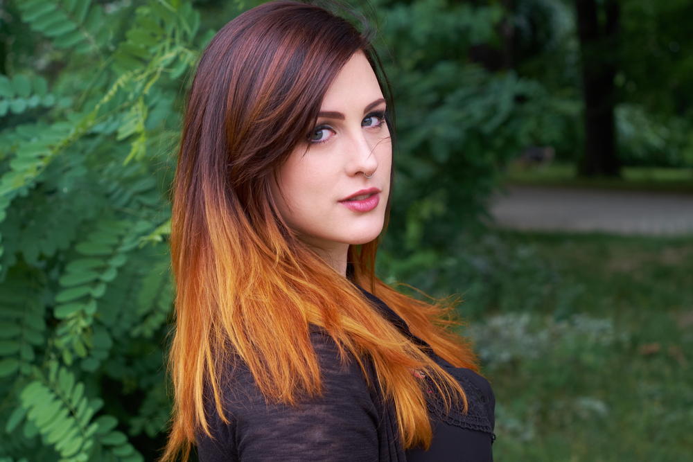 Woman with auburn highlights pictured outside to illustrate the best hair colors for neutral skin tones